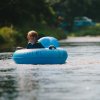 Boy sitting in blue inner tube in river smiling at camera