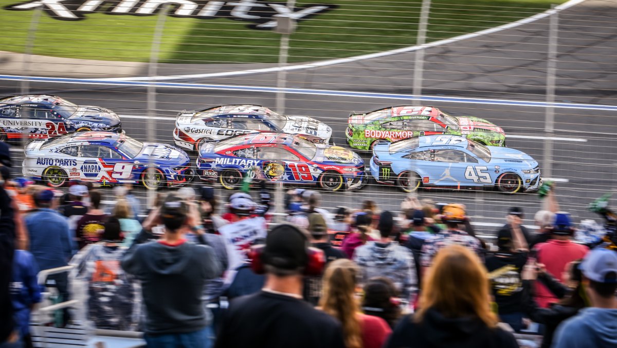 Fans in stands watching NASCAR race at Charlotte Motor Speedway.