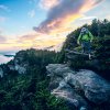 Person hiking down from peak of mountain surrounded by trees and views