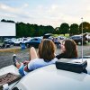 Two friends sitting on hood of the car waiting for drive-in movie to start