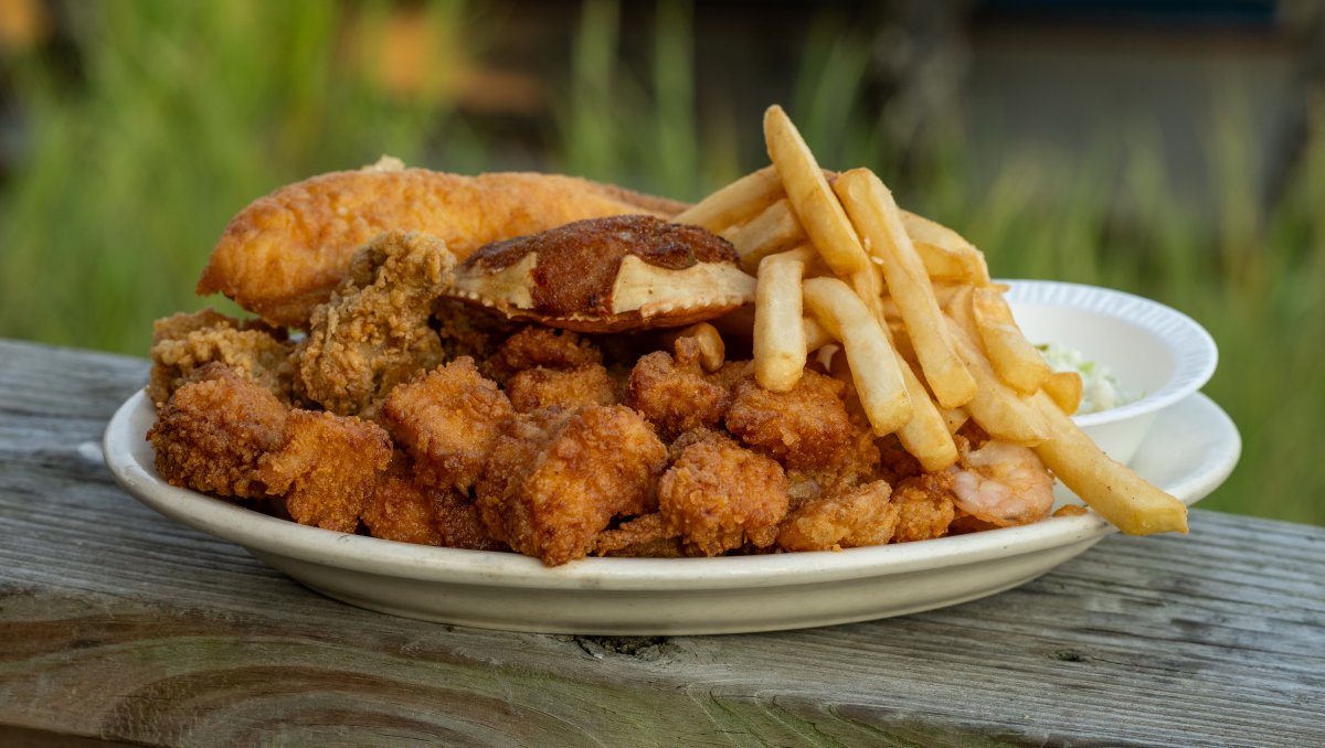 Closeup of Calabash seafood plate sitting on wood railing.