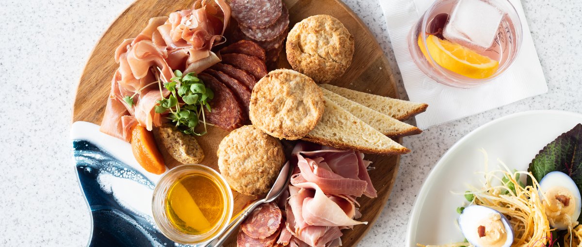 Overhead of charcuterie board, salad and cocktail at restaurant.