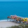 Pier with tiki bar jutting into bright blue ocean in Carolina Beach.