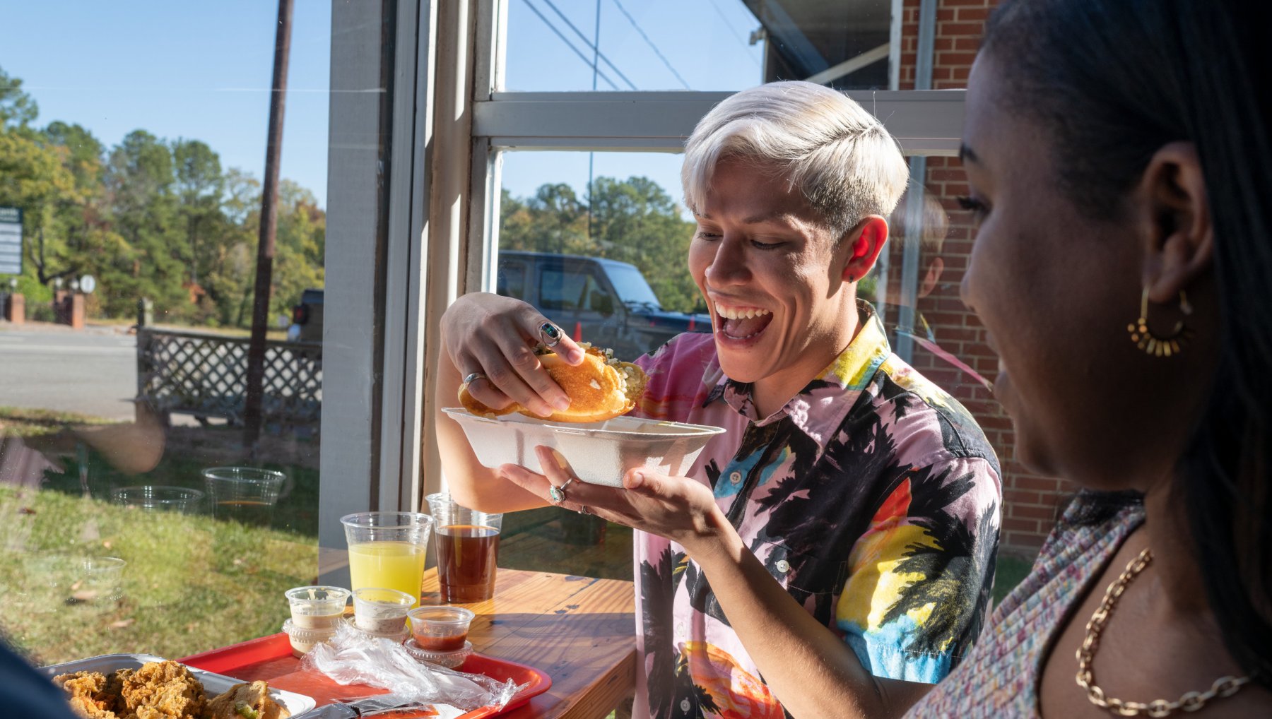 Two friends enjoying seafood sandwiches at Saltbox Seafood Joint in Durham.