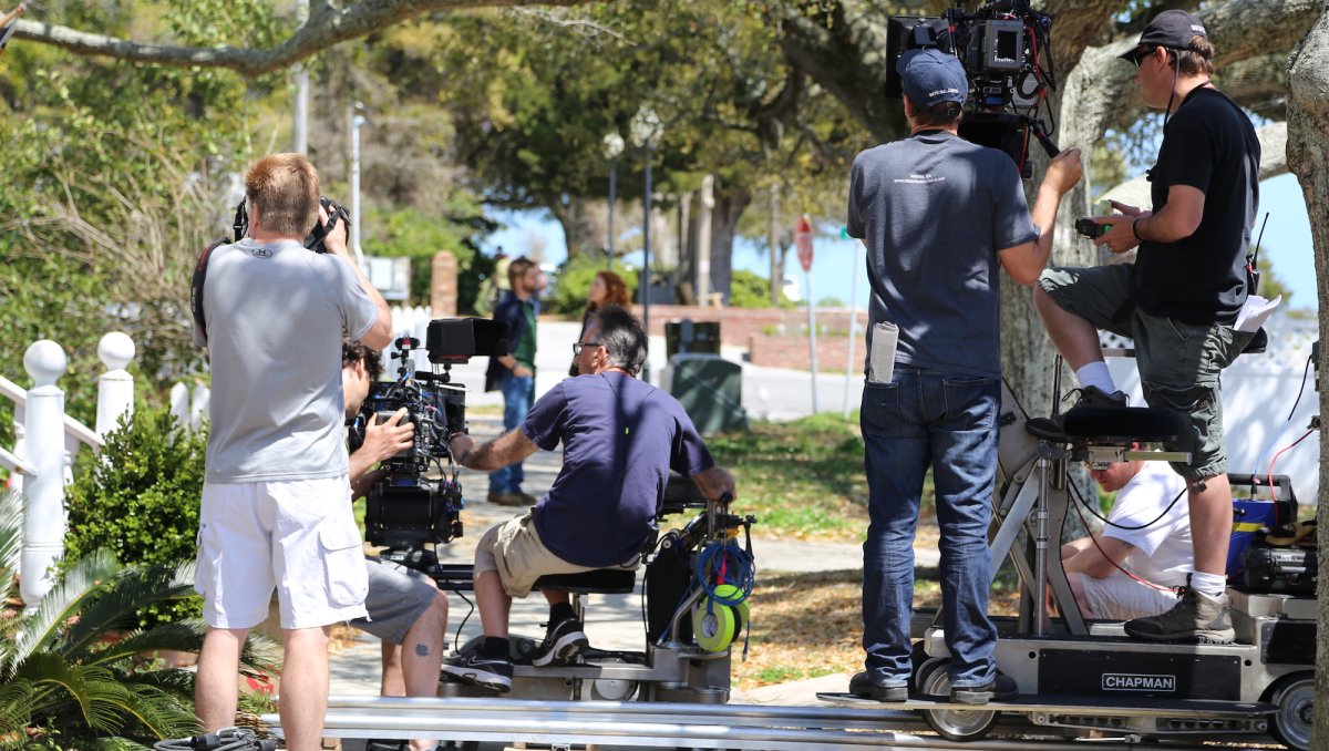 Film crew working behind the scenes of TV show or movie during daytime.