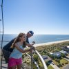 Father and daughter at top of Oak Island Lighthouse overlooking beach and water.