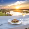 Plate of food and glass of wine on ledge overlooking marsh and creek at Jinks Creek Waterfront Grille.