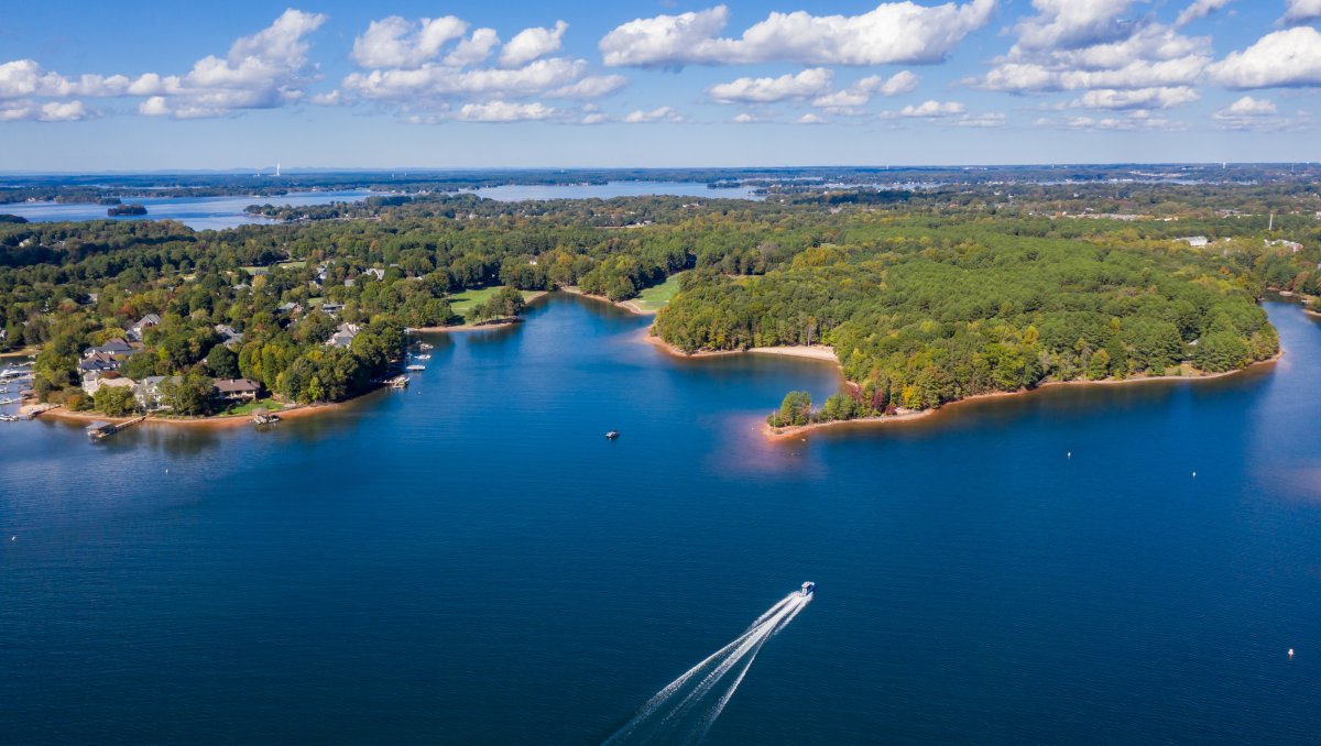 Aerial of boat on Lake Norman with shore and land in distance.