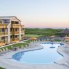 Overview of pool, grounds and exterior of hotel with ocean in background at Sanderling Resort.
