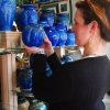 Woman holding blue piece of pottery inside gallery in Seagrove.