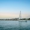 Sailboat on water with houses in background on shore