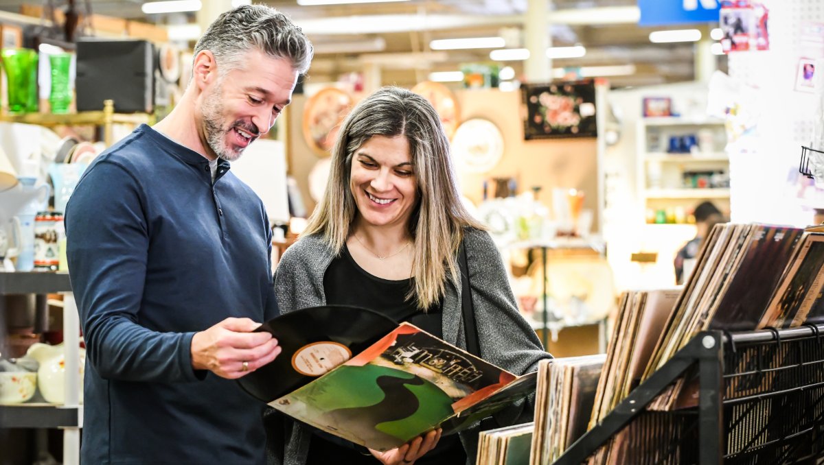 Man and woman looking at vinyl record at antique store.