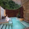 Woman in robe sitting on edge of plunge pool outside at The Umstead Spa.