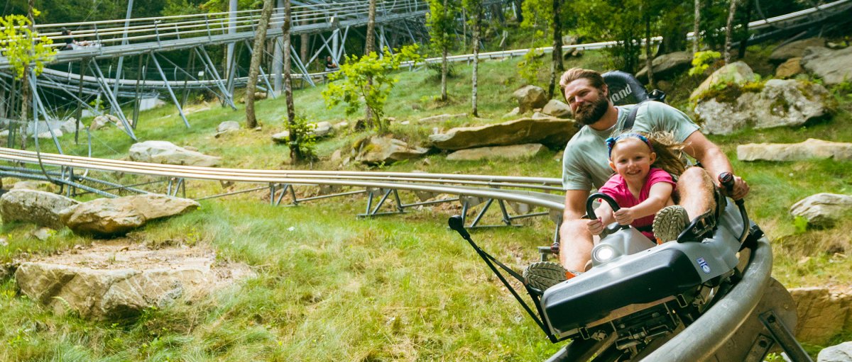 Father and child riding Wilderness Run coaster during summer.